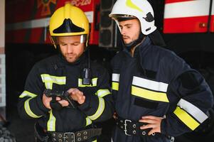 Portrait of two firefighters in fire fighting operation, fireman in protective clothing and helmet using tablet computer in action fighting photo