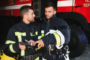 Portrait of two firefighters in fire fighting operation, fireman in protective clothing and helmet using tablet computer in action fighting photo