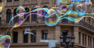 Many multicolored giant soap bubbles flying in the air on a windy day. Huge bubble are stretching on the wind into long smoothy changing form without popping. Close up. Copy space. Selective focus. photo