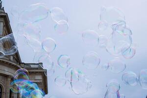 Large multicolored soap bubbles flying in the cloudy sky. Big bubble outdoors in the spring or summer street. Frankfurt, Alte Oper on background. Simple creative concept. Close-up. Copy space photo