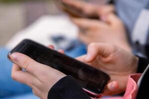 Point finger on screen of mobile phone. Person texting text message, hipster touch smartphone screen. Girl hands holding scrolling chatting working. Summer park. Close up. Copy space. Selective focus photo
