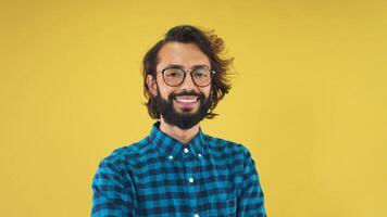 Portrait of a young man standing over isolated yellow background smiling happy looking at camera video