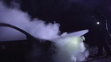 Unrecognizable firefighters combating a fire on a car with water hose. video