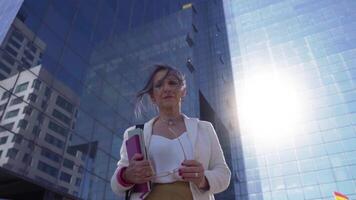 Middle-aged Caucasian business woman looking at camera. Beautiful mature lady smiling with books and tablet. video