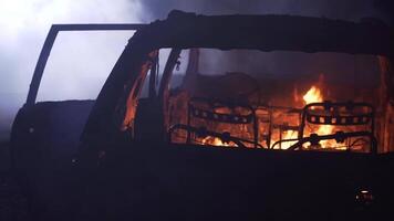 Cinematic film shot of a car burning in flames after a car crash at night in slow motion. video