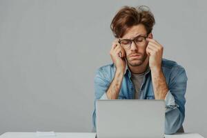 Man sitting at the table with laptop looking confused. photo