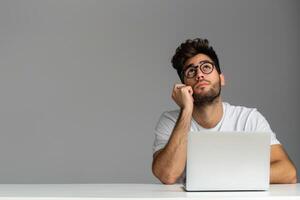 Man sitting at the table with laptop looking confused. photo