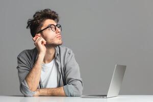 Man sitting at the table with laptop looking confused. photo