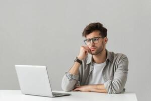 Man sitting at the table with laptop looking confused. photo