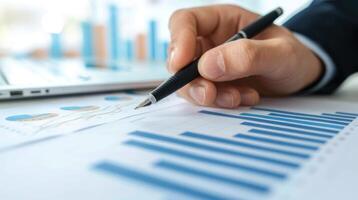 Close up of a businessman's hand holding a pen working with a financial chart and data on a desk in an office. photo