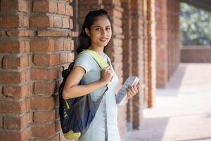 A College Student is Carrying a Bag On His Shoulder and Books in His Hand photo