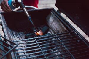 Man using BBQ lighter torch to start fire for charcoal. photo