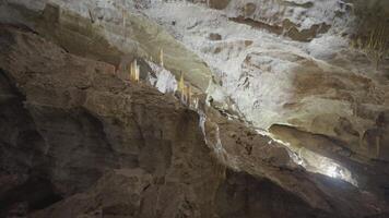 Underground cave formations of stalactites and stalagmites. Action. View inside of a cavern on giant stone walls. video