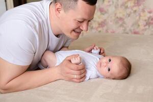 close-up dad plays with a small child at home on the bed. parent hugging a small child. family concept photo