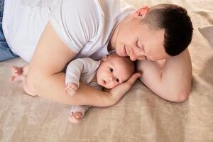 close-up dad plays with a small child at home on the bed. parent hugging a small child. family concept photo