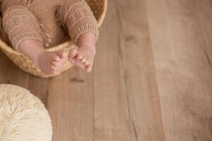 close-up of baby's legs in a wicker cradle.beige background with space for text photo