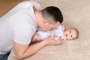 close-up dad plays with a small child at home on the bed. parent hugging a small child. family concept photo