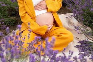 pregnant woman in a beautiful orange suit hugging her belly in a field with lavender. pregnancy concept photo