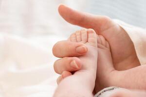 the parent's hand holds the baby's small leg, light close-up photo. family concept. background with place for text photo