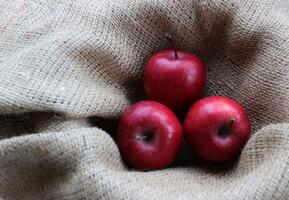 Three red apples in a fruit basket lined with burlap top view photo