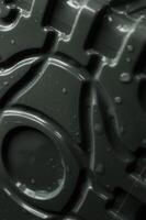 Droplets on a dark plastic surface with depressed curved lines and circle pattern close up angle view photo