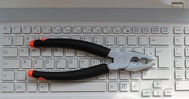 White Buttons Of Notebook Keyboard With Mechanic Pliers On It. Stock Photo For Computer Service Illustration