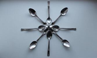 Flower Pattern Made With Variety Size Spoons On White Surface photo