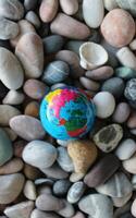 Top view of the North Pole on a miniature Earth globe on smooth rocks. Vertical stock photo for travel backgrounds