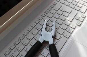 Computer Repairing Concept. Steel Pliers On Laptop Keyboard Angle View photo