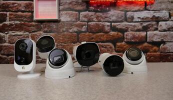 Security cameras of different types are laid out in a row on a demonstration table photo