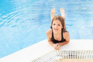 Smiling cute little girl wearing sunglasses in the pool on a sunny day photo