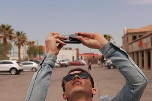 Young Man Looking at the Sun and taking photos During a Solar Eclipse using a Black Obsidian Stone