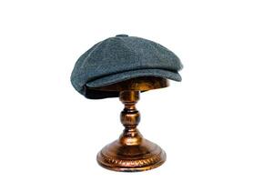 Concept photo of a classic newsboy hat with eight panels made of warm wool. A classic dark charcoal hat is mounted on a bronze mannequin head against a white studio background