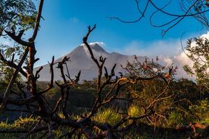 Panorama of Mount Merapi at dusk is very clear with the blue sky and green forest in the foreground with a ravine where cold lava flows. The landscape of Mount Merapi is truly enchanting and charming photo