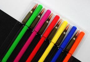 Closed felt tip pens and loaded cartridges are laid out in a case on a background divided into a white and black field photo