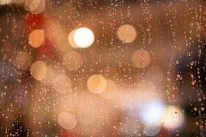 Raindrops water droplets trickling down on wet clear window glass during heavy rain against blurred background. rain and bokeh. photo