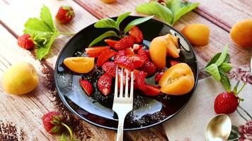 fresh fruit salad of ripe strawberries and apricots, on a light wooden table video