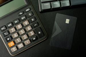 Calculator and Credit card on black background. Business idea or engineering context. Top view with copy space. photo