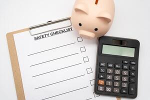 Blank Safety checklist with Calculator and Piggy Bank. safety for Business. Empty safety checklist form on white background. saving money for protection, planning in future. photo