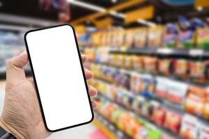 Hand holding blank screen smartphone for copy space on blurred Miscellaneous Product shelf. e-commerce app shopping mockup. social media, payment and shopping online concept. photo