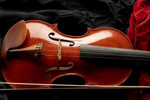 Close up of a violin with bow on a background of black and red fabrics photo