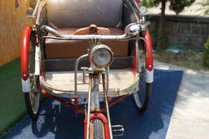 Front view of old ancient Thailand tricycle. The structure is made of strong metal, with a headlight, handlebars, bell, and rider seat. passenger seat It is beautifully designed. photo