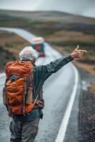 senior man with backpack on road pointing to bus photo