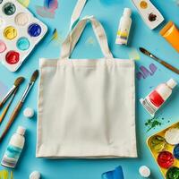 a white canvas bag with paint and brushes on a blue background photo