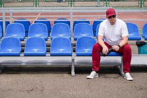 sportsman with a bottle of water sitting and resting at the seats at the stadium photo
