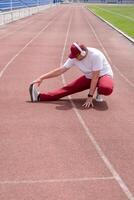 Athletic bearded man warms up before workout at the stadium photo