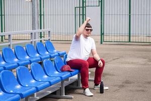 sportsman with a bottle of water sitting and resting at the seats at the stadium photo