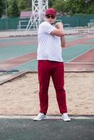 Athletic bearded man warms up before workout at the stadium photo