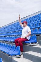 sportsman with a bottle of water sitting and resting at the seats at the stadium photo