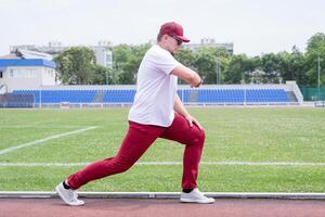 Athletic bearded man warms up before workout at the stadium photo